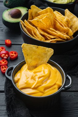 Nachos corn tortilla cipsi peynir soslu, siyah ahşap arka planda.
