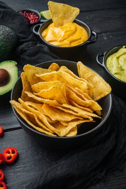 Mısır tortilla cipsi nacho ve sos, siyah ahşap arka planda.