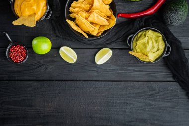 Nachos mısır cipsi geleneksel sos seti, siyah ahşap arkaplan, üst görünüm veya düz metin alanı ile fotokopi