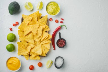 Krem soslu nacho tortilla, beyaz arka planda guacamole ve peynir sosu ile servis edilir.
