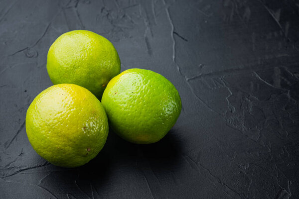 Ripe green lime set, on black background with copy space for text