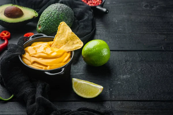 Peynir soslu kase, nacho, siyah ahşap arkaplan ve metin için kopya alanı