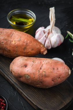 Siyah arka planda bitkiler ve baharatlarla dolu çiğ patates..