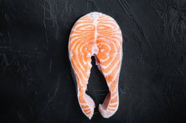 Çiğ somon bifteği, siyah arkaplan, düz görünüm ve metin için boşluk..