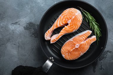 Izgara tavada somon bifteği çiğ balık, gri arkaplan üzerinde, metin için üst görünüm.