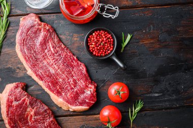 Baharatlı çiğ organik biftekler, biberiye, tpmatorler, baharatlı biber yağı ve kırsal koyu ahşap zemin üzerine nar, metin için üst görüş alanı