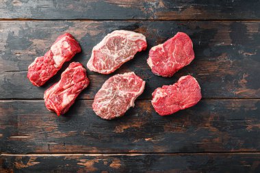 Çeşit çeşit organik çiğ sığır eti bifteği kıçı, chuck roll ve üst bıçak kesme eski kırsal ahşap arka plan, üst görünüm metin için alan