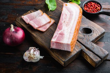 Tütsülenmiş domuz pastırması, ahşap yüzeyde bitkilerle dolu..