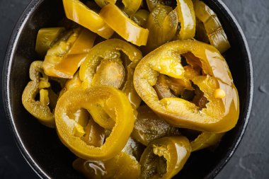 Ev yapımı baharatlı jalapeno biberi marine edilmiş, siyah arka planda, düz manzaralı.