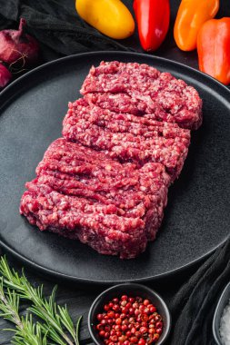 Kıyma. Siyah ahşap masa arkasında yemek pişirmek için gerekli malzemelerle yer eti.