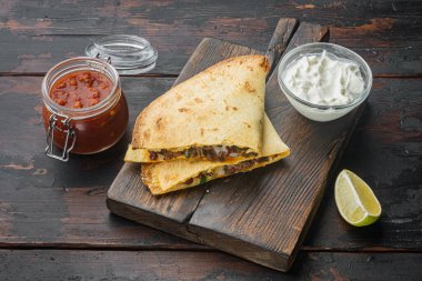 Tavuk, peynir ve biberli Quesadilla, eski siyah ahşap masa arkasında.
