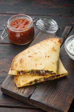 Meksika quesadilla dürümü. Tavuk, mısır, tatlı biber ve salsa sosu. Eski, siyah ahşap masa arkasında.