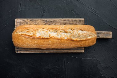 Taze pişmiş baget ekmeği, siyah arka planda, üst manzara düz yatıyordu.