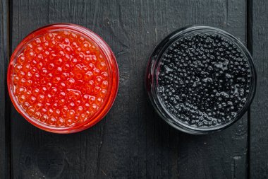 Siyah ve kırmızı havyarlı cam kavanoz, siyah ahşap masa arkaplanı, üst görünüm düz