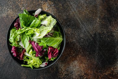 Parçalanmış salata ile karışık kaseler taze marul yaprakları, eski koyu kırsal arka planda, üst görünüm düz metin alanı ile yatıyordu