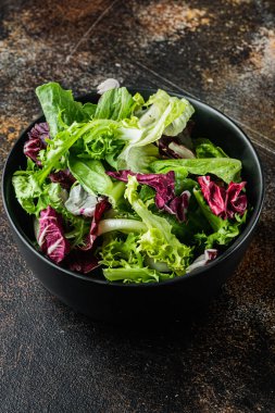 Farklı marul salatalarından taze yapraklar, eski koyu kırsal arka planda.