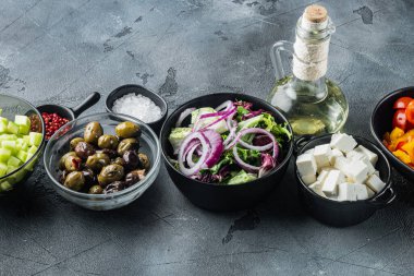 Geleneksel Yunan salatası, domates, soğan, zeytin, feta peyniri için gri arka planda malzemeler