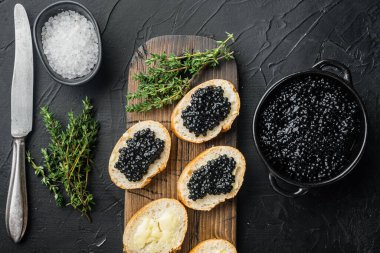 Siyah mersin balığı havyarlı kanepe, siyah arka planda, üst manzara düz.