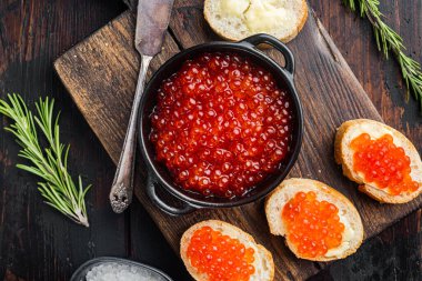 Kırmızı havyarlı kanape tostları, eski koyu ahşap masa arka planında, üst manzara düz yatıyordu