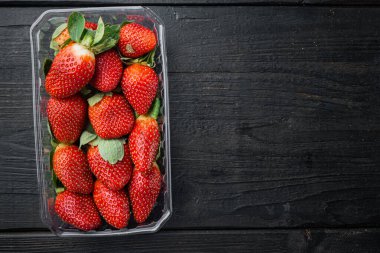 Çilekli tepsi, siyah ahşap masa arkaplanı, üst görünüm düz metin için metin alanı ile yatar