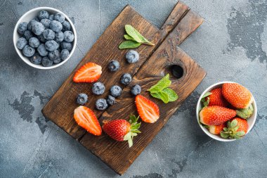 Taze sulu olgun çilekler, mavi böğürtlenler, gri arka planda, üst manzara düz yatıyordu.