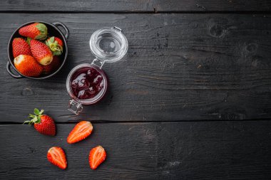Ev yapımı lezzetli çilek reçeli ve taze berrie ile, siyah ahşap masa arkaplanı, üst görünüm düz metin alanı ile yatıyordu
