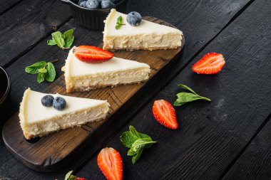 Berrie ile cheesecake 'in bir kısmı, metin için kopyalama alanı olan siyah ahşap masa arkaplanı üzerine.