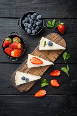 Klasik New York Cheesecake, dilimlenmiş, siyah ahşap masa arkaplanı, üst manzara düz.