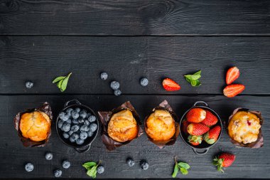 Yaban mersinli çörekler, siyah ahşap masa arkaplanı, üst görünüm düz metin alanı için fotokopi alanı ile yatıyordu
