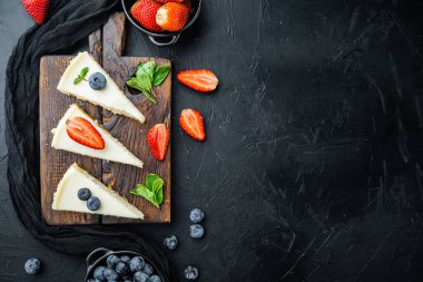 Blueberrie ve çilekli cheesecake, siyah arka planda, üst görünüm düz metin için metin alanı ile yatıyordu