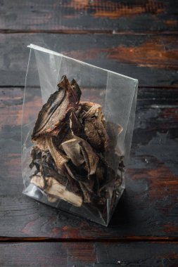 Boletus kurutulmuş mantar seti, eski siyah ahşap masa arka planında, plastik pakette.