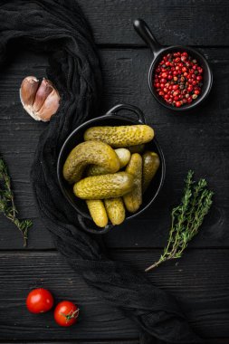 Terbiye edilmiş salatalık turşusu seti, siyah ahşap masa arkaplanı, üst görünüm düz