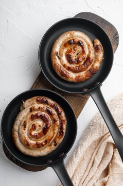 Ev yapımı ızgara sosis, dökme demir kızartma tavasında, beyaz arka planda, düz manzaralı.