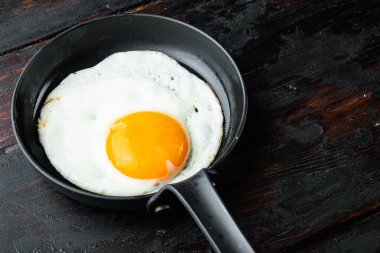 Yağda yumurta ve domuz yağı, ekmek ve yeşil tüy dökme demir tava, eski siyah ahşap masa arka planda, metin kopyalanacak yer