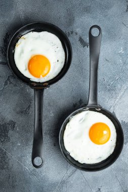 Kızarmış yumurta, kiraz domatesli ve kahvaltıda ekmek, dökme demir tavada, gri arka planda, düz manzaralı