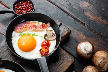 Yağda yumurta ve domuz yağı, ekmek ve yeşil tüy dökme demir tava, eski siyah ahşap masa arka planda, metin kopyalanacak yer