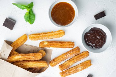 Şeker ve çikolata soslu Churros, beyaz arka planda, üst manzara düz yatıyordu.