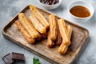 Tipik İspanyol çerezi churros, kızarmış hamur pastası genellikle çikolata karamelli acı sos setiyle servis edilir, gri arka planda.