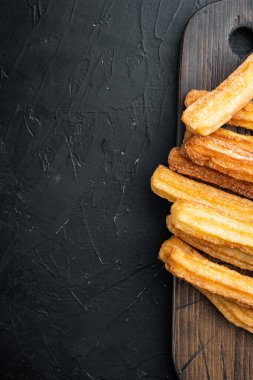 Karamelli Churros, geleneksel İspanyol dişi, siyah arkaplanda, üst görünüm düz metin, kopyalanma alanı