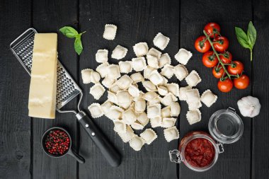 Ev yapımı İtalyan mantı makarna seti, siyah ahşap masa arkaplanı, üst manzara düz.