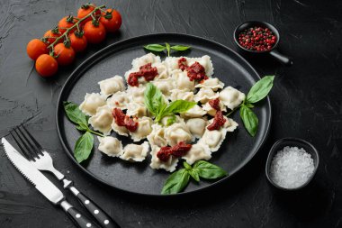 Domates soslu ravioli, peynir ve fesleğen, fesleğen, parmesan ve siyah tabakta domates.