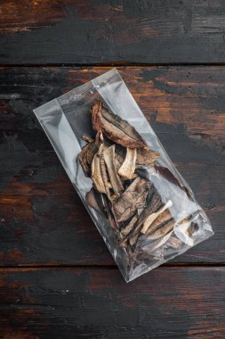 Kurutulmuş porcini mantarları, eski koyu ahşap masa zemininde, plastik pakette, düz manzaralı.
