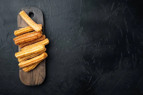 Churros pudra şekeri serpiştirilmiş, siyah arkaplan üzerine, üst görünüm düz metin, kopyalanma alanı ile yatıyordu