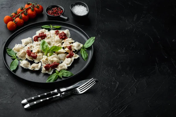 Domates soslu ravioli, peynir ve fesleğenli fesleğen, siyah tabakta parmesan ve domates, siyah arkaplan, metin için metin alanı ve boşluk.