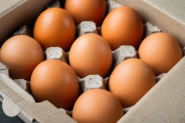 Raw chicken eggs in egg box set, on black background