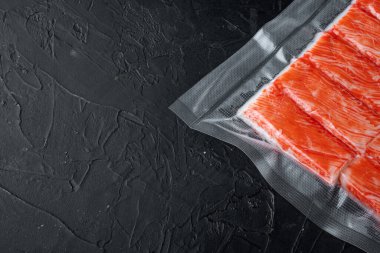 Yengeç balığı eti vakum paketi setinde, siyah arkaplanda, telif alanı ve metin için yeri olan üst görünüm düzleminde
