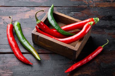 Kırmızı ve yeşil biber seti, ahşap kutuda, koyu ahşap arka planda.