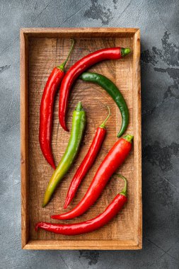 Olgun kırmızı ve yeşil biber seti, ahşap kutuda, gri arka planda, üst manzara düz