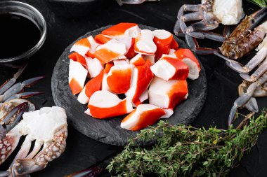 Siyah arka planda mavi yüzen yengeç takımlı taze yengeç surimi.