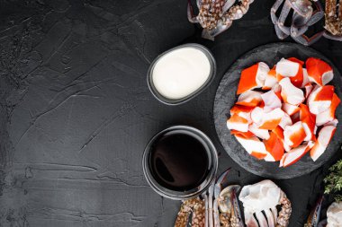 Yengeç çubukları, yarı pişmiş balık kıyması, mavi yüzme yengeci seti, siyah arkaplan, üst görünüm düz, metin için telif alanı ve boşluk